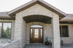 Exterior view of a brick home featuring a large double door entryway, emphasizing door replacement options from The Window & Door Store.