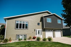Modern two-story house featuring new siding, multiple windows, and a landscaped front yard, showcasing The Window & Door Store's home improvement projects.
