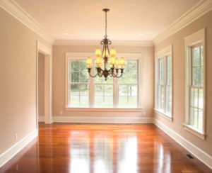 Large interior windows surrounding living room with wood floor.