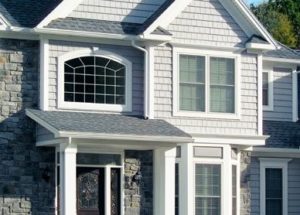 Gray suburban home with rockwork and white accented windows.