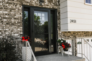 Concrete steps lead up to beautiful black steel entry door surrounded by stone accent
